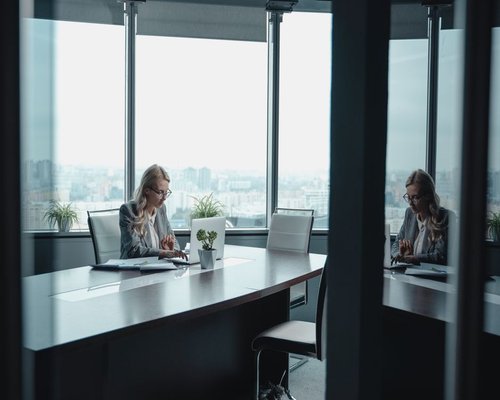A focused local professional working at a spacious desk by the window in a high-rise Singapore apartment